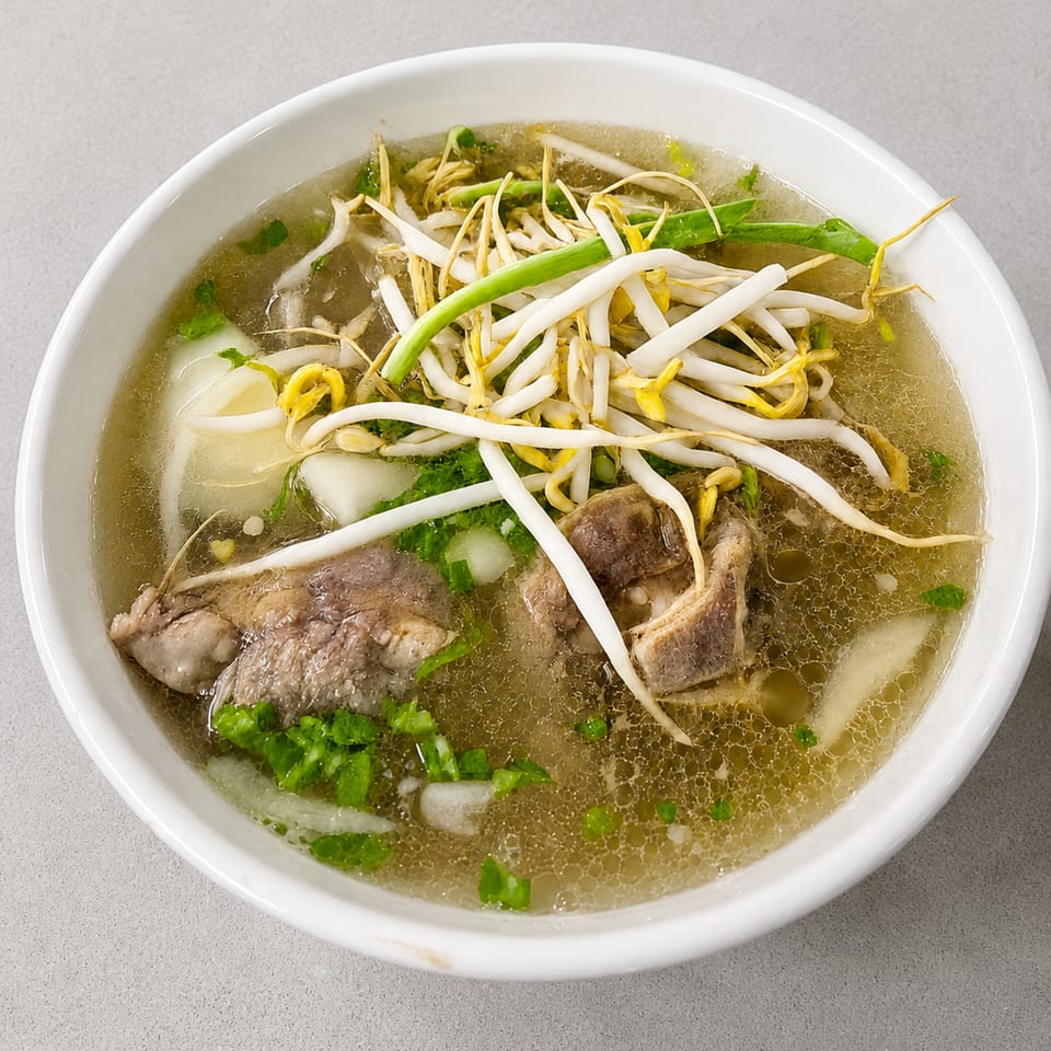 Close-up of a bowl of pho with beef, bean sprouts, and green onions in a clear broth.